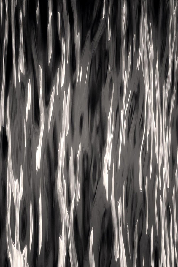 Abstract black and white wavy pattern with fluid, metallic-looking vertical streaks and organic splatter-like shapes.